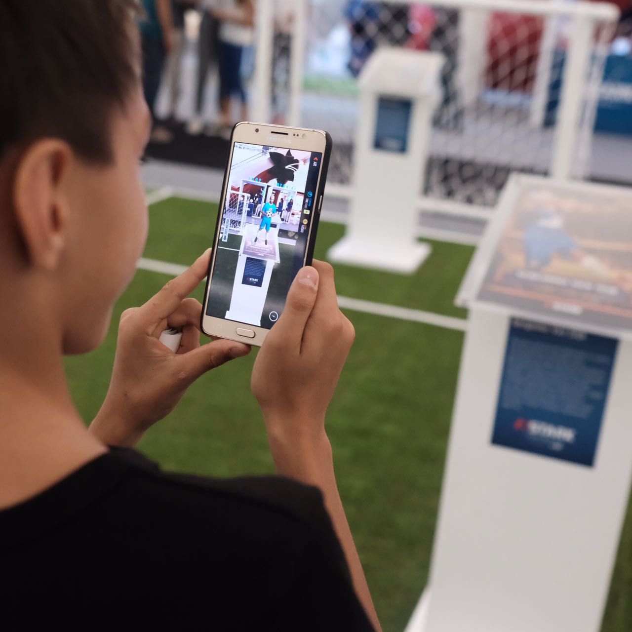 Salah satu pengunjung pusat perbelanjaan di bilangan Senayan, mencoba memainkan ASTARK Football, aplikasi trading card games sepak bola pertama yang menggunakan teknologi augmented reality (AR). Mobile gaming apps ini hadir untuk menghubungkan penggemar sepak bola di tanah air dengan pemain sepak bola favorit mereka. Dengan teknologi AR trading cards tersebut, ASTARK mampu menghadirkan permainan sepak bola online menjadi lebih nyata. (ASRARK)