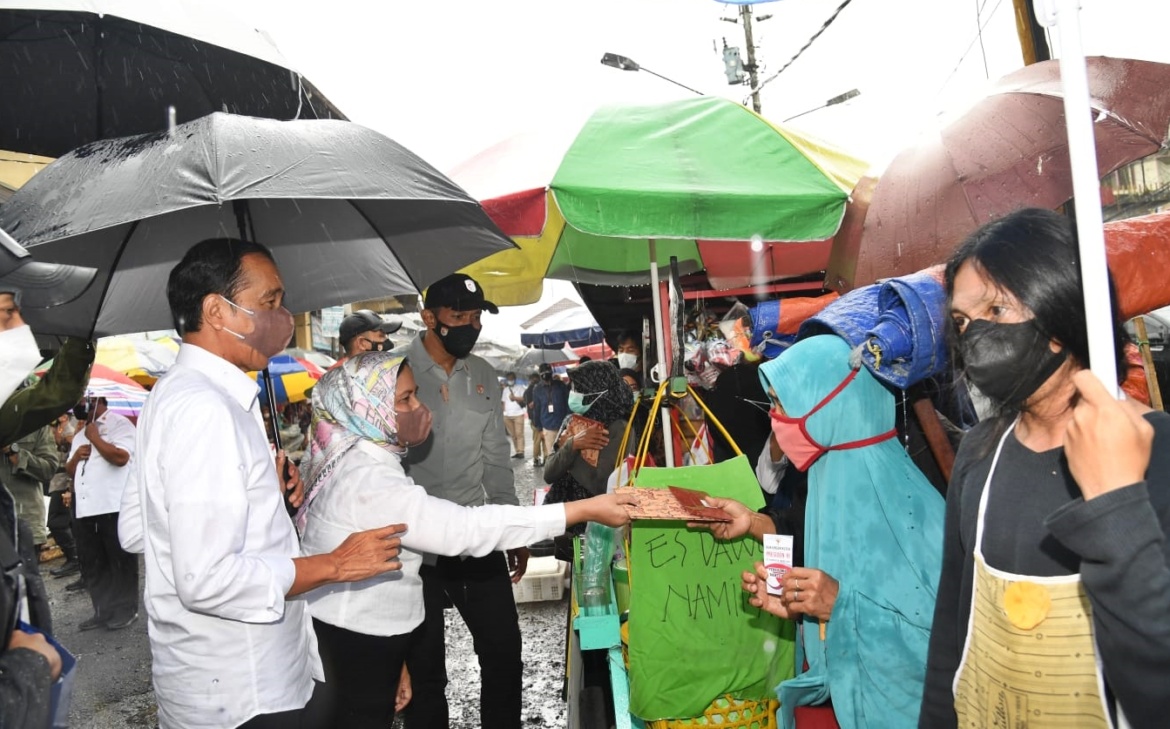 Photo Credit: Presiden Joko Widodo (Jokowi) menyerahkan bantuan tunai untuk pedagang kaki lima dan warung yang sehari-hari berjualan di Pasar Kertek di Wonosobo, Jawa Tengah (Jateng), Selasa (14/12/2021). FILE/BPMI