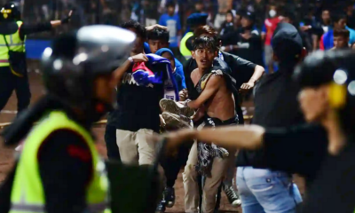 Sekelompok suporter membawa seorang korban pria di stadion Kanjuruhan, Malang selama huru-hara keributan terjadi. AFP/Getty Images