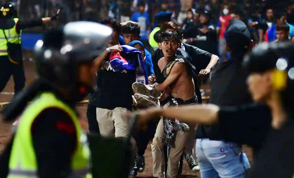 Sekelompok suporter membawa seorang korban pria di stadion Kanjuruhan, Malang selama huru-hara keributan terjadi. AFP/Getty Images